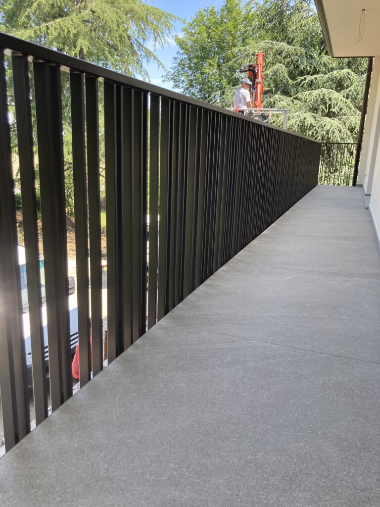 Parapetto balcone in ferro, con elementi verticali, minimali e moderni, di colore antracite scuro.