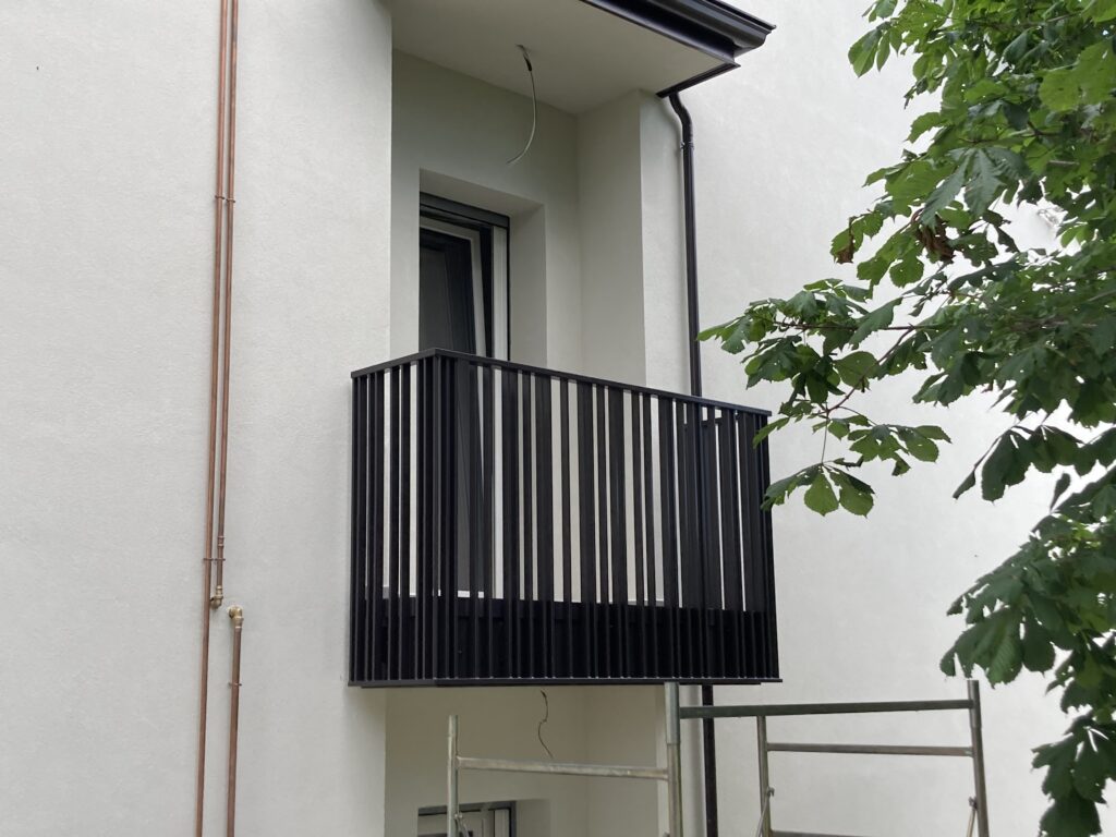 Parapetto balcone in ferro, con elementi verticali, minimali e moderni, di colore antracite scuro.