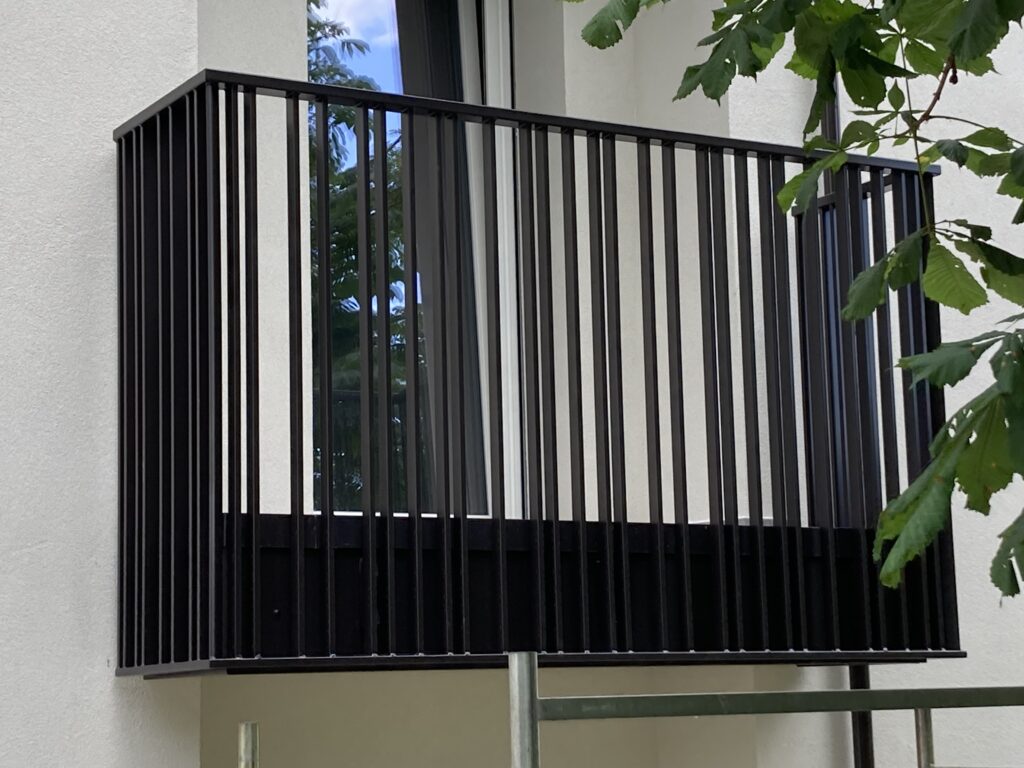 Parapetto balcone in ferro, con elementi verticali, minimali e moderni, di colore antracite scuro.